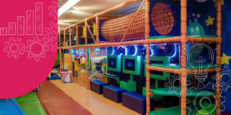 Área de lazer infantil em restaurante com playground colorido, crianças brincando, escorregador vermelho, balanços azuis, e decoração temática de animais.