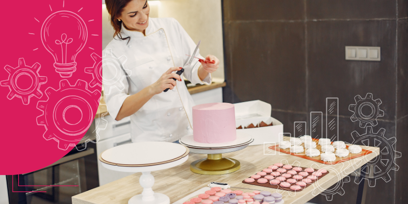 Baker alegre em uniforme branco atrás do balcão de vidro em padaria com pães e bolos diversos em exposição.