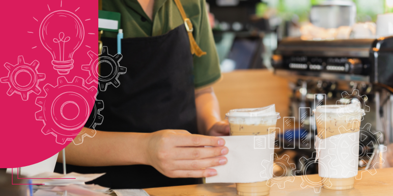 Barista servindo café a um cliente em uma cafeteria aconchegante com mesa de madeira e luz acolhedora.