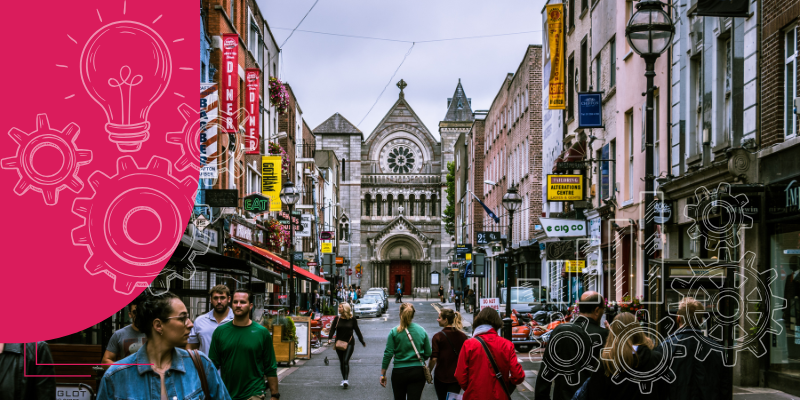 Pessoas comprando em um mercado de rua, cercadas por frutas coloridas e especiarias aromáticas sob um céu azul claro.