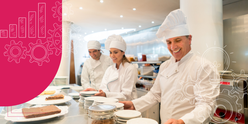 Cozinha de restaurante movimentada com chefs em uniformes brancos preparando pratos.
