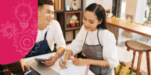 Chef em cozinha organizando documentos financeiros coloridos em mesa de madeira, rodeado por vegetais e utensílios de cozinha.